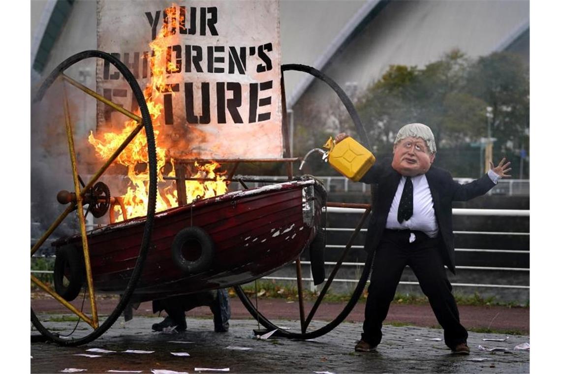 UN-Klimachefin: Ohne Änderungen droht „düstere Zukunft“ Ein Darsteller von Ocean Rebellion hat sich als der britische Premierminister Johnson verkleidet und zündet das Segel eines kleinen Bootes mit der Aufschrift "Your Children's Future" an. Foto: Andrew Milligan/PA Wire/dpa