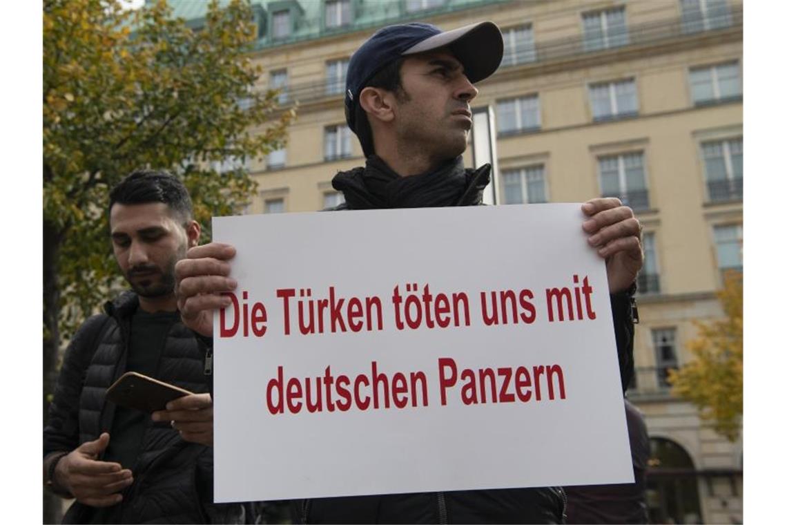 Ein Demonstrant hält bei einer Demonstration gegen die türkische Militäroffensive in Nordsyrien am Pariser Platz in Berlin ein Protestplakat. Foto: Paul Zinken/dpa