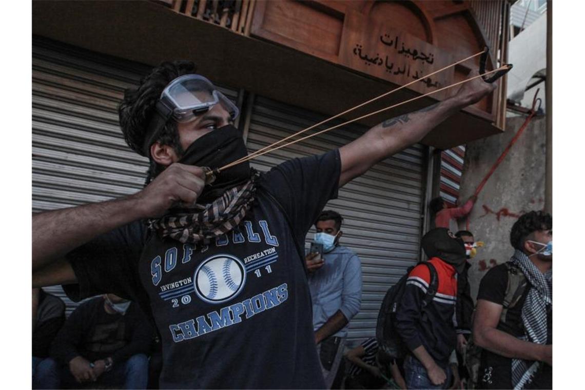 Ein Demonstrant in Bagdad zielt mit einer Steinschleuder auf Einsatzkräfte. Foto: Ameer Al Mohammedaw/dpa