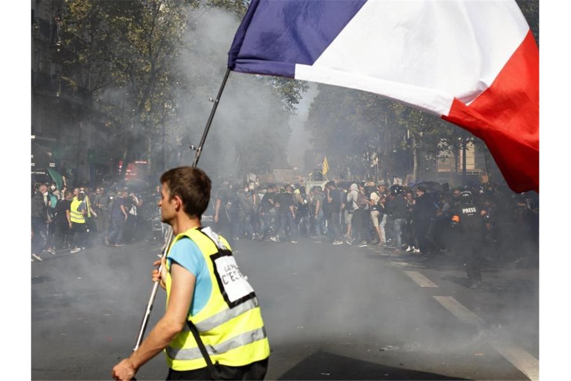 Ein Demonstrant mit gelber Weste trägt bei den Protesten eine französische Flagge. Foto: Thibault Camus/AP