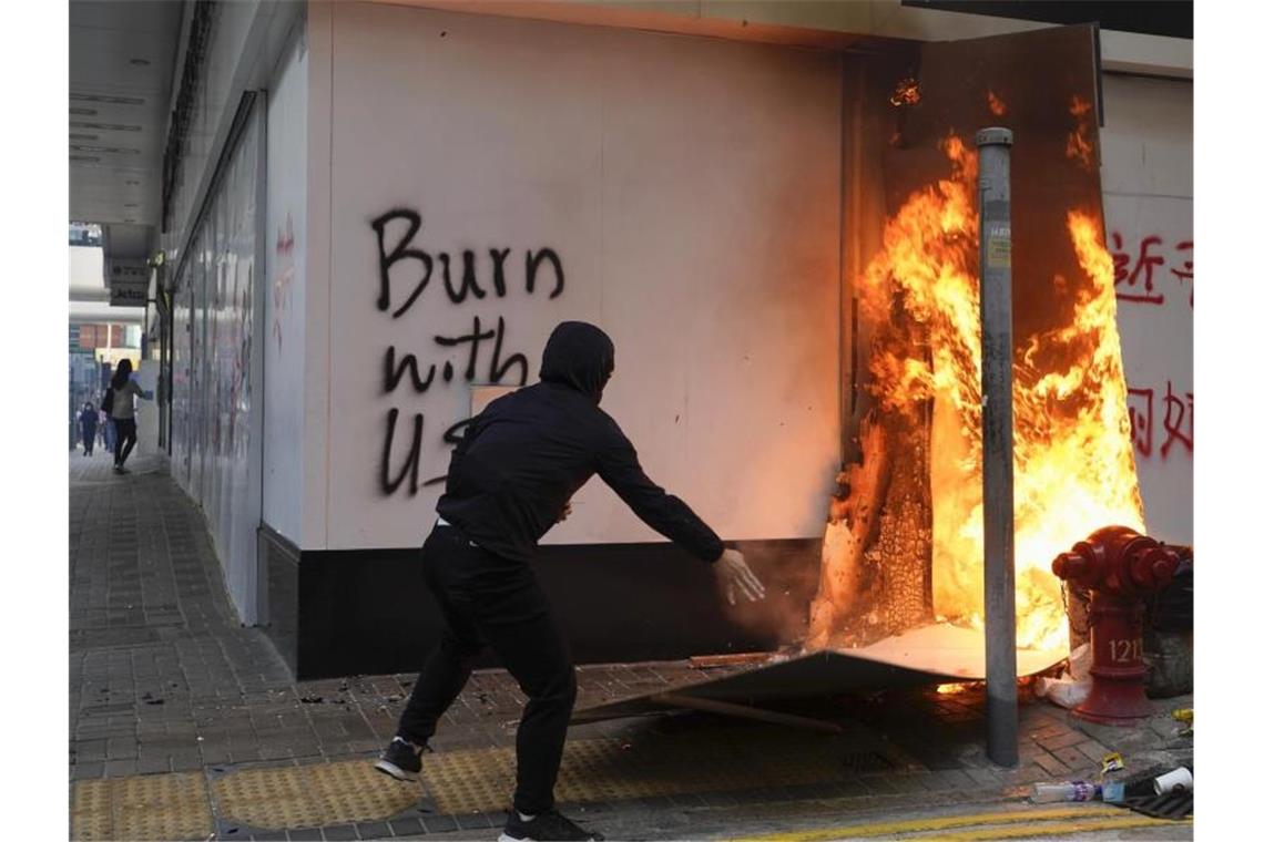 Ein Demonstrant setzt außerhalb der Bank of China im Central District von Hongkong Kartons in Brand. Foto: Vincent Yu/AP/dpa
