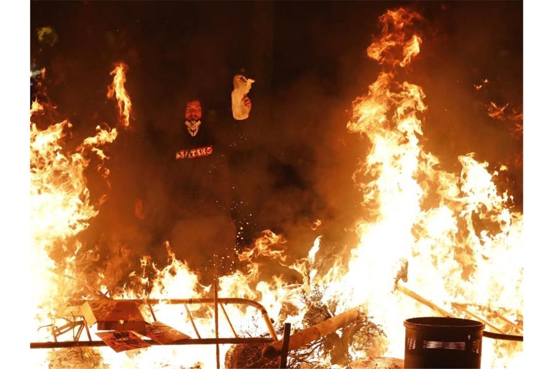 Ein Demonstrant steht in der Nacht vor einer brennenden Barrikade. Foto: Emilio Morenatti/AP/dpa
