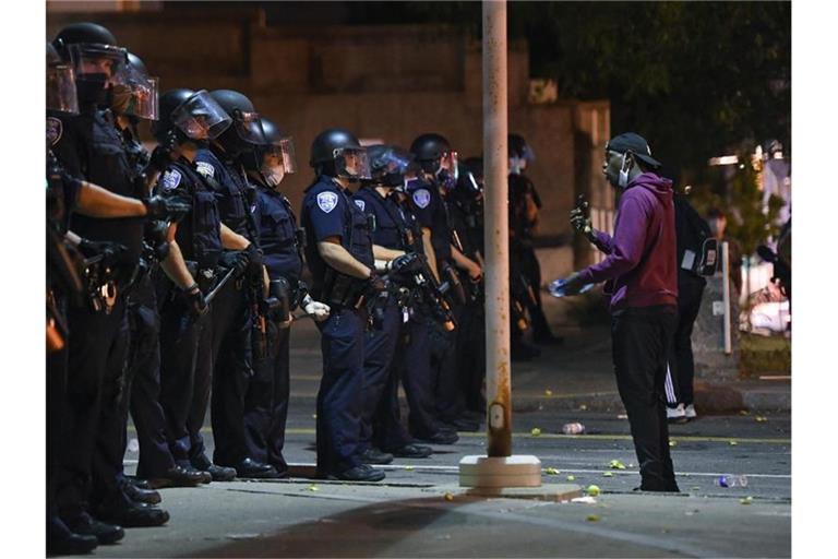 Ein Demonstrant steht während einer Demonstration vor Polizisten in Rochester. Nachdem ein 41-jähriger Afroamerikaner infolge eines brutalen Polizeieinsatzes verstarb, wurden sieben Beamte vom Dienst suspendiert. Foto: Adrian Kraus/AP/dpa
