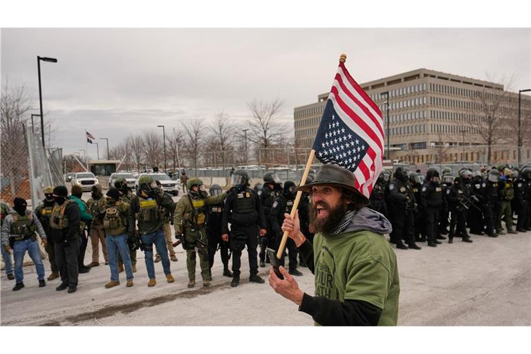 Ein Demonstrant trägt eine umgedrehte US-Fahne vor den Beamten der Einwanderungsbehörde ICE bei einem Protest gegen die Behörde vor dem Bishop Henry Whipple Federal Building.