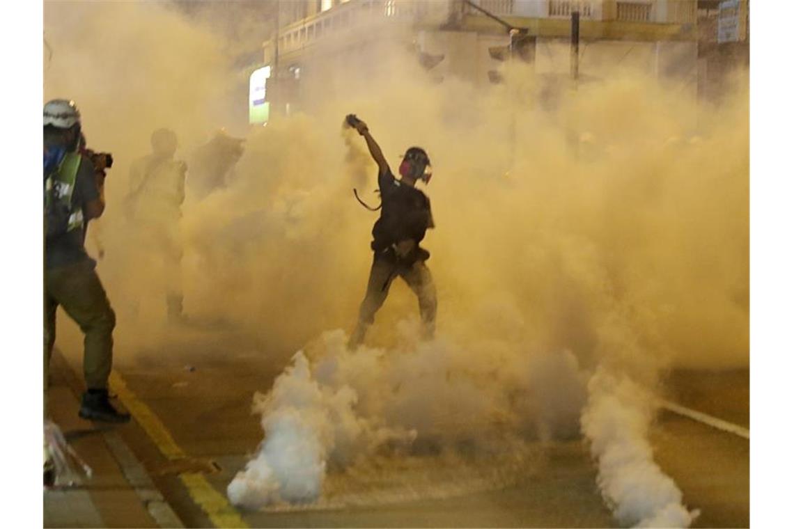 Hongkonger wollen Arbeit niederlegen Ein Demonstrant wirft bei einer Konfrontation mit der Polizei einen Tränengasbehälter zurück. Foto: Vincent Thian/AP