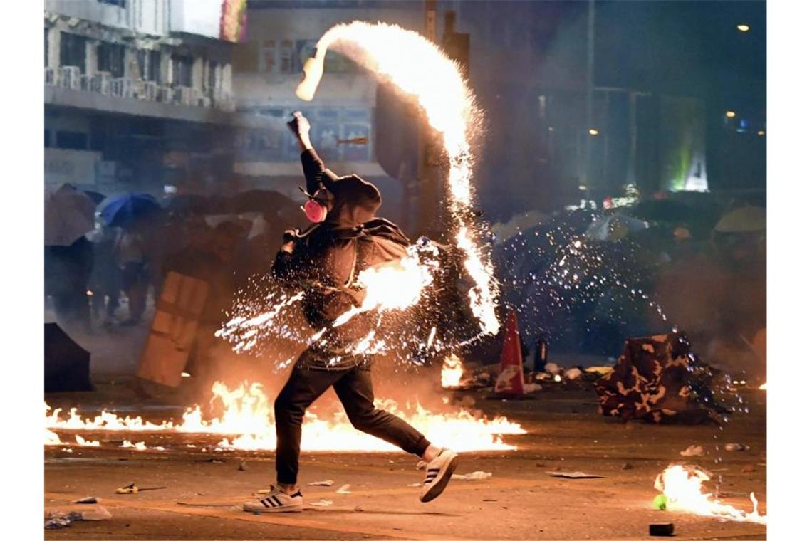 Ein Demonstrant wirft einen Molotowcocktail auf die Polizei. Foto: -/kyodo/dpa