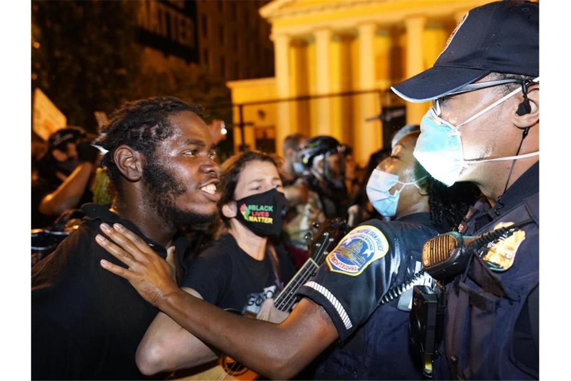 Ein Demonstranten spricht mit einer Polizistin während eines Protests gegen US-Präsident Trump auf dem „Black Lives Matter“-Plaza. Foto: Julio Cortez/AP/dpa