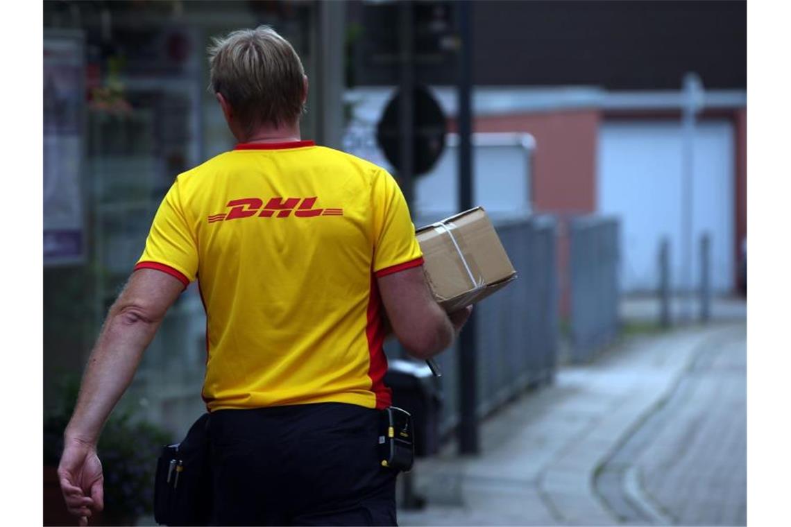 Ein DHL-Mitarbeiter liefert ein Paket aus. Foto: picture alliance / dpa