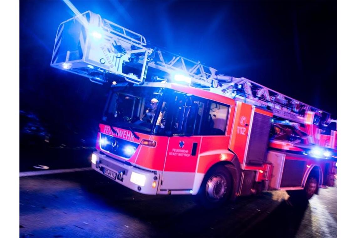 Ein Drehleiterwagen der Feuerwehr fährt mit Blaulicht über eine Straße. Foto: Marcel Kusch/Archivbild