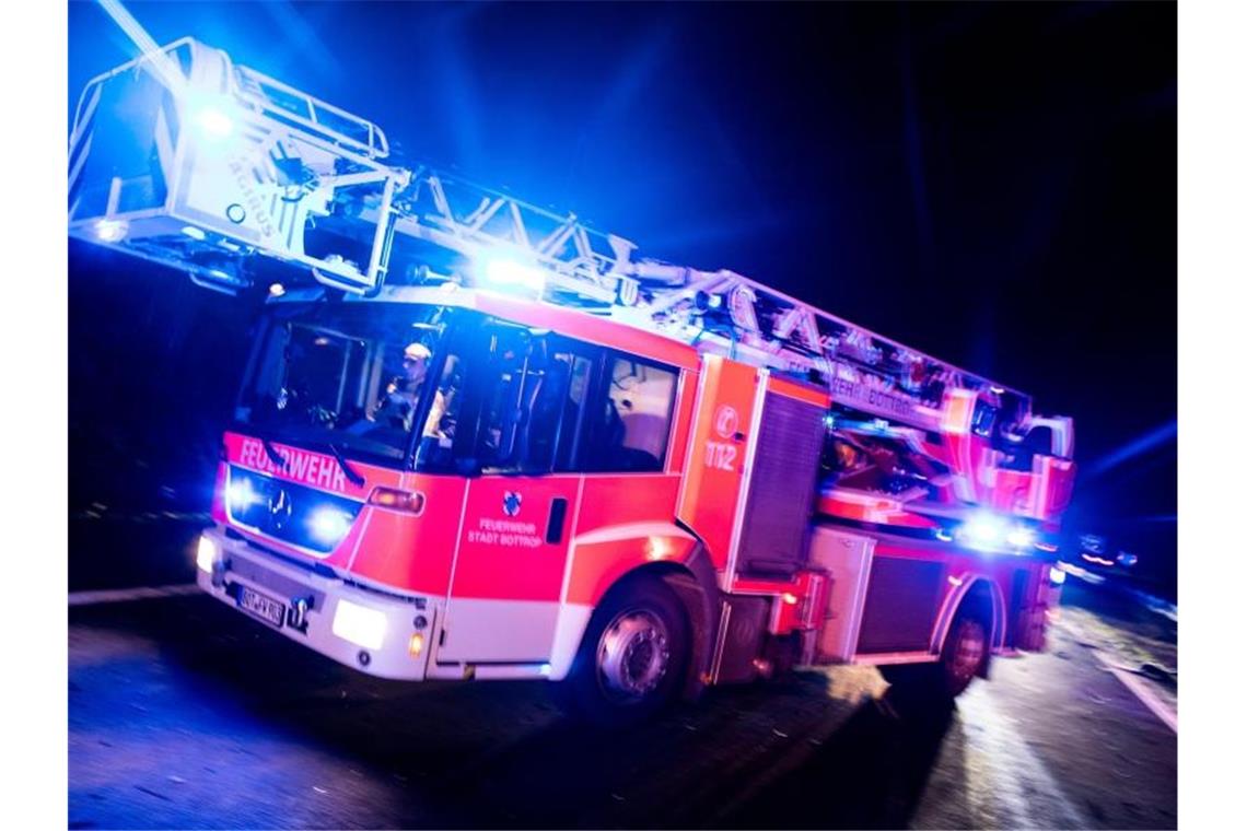 Ein Drehleiterwagen der Feuerwehr fährt mit Blaulicht an einer Unfallstelle vorbei. Foto: Marcel Kusch/dpa/Illustration