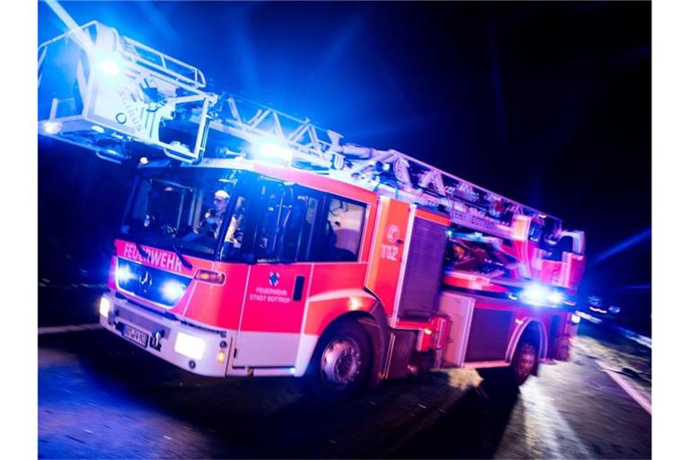 Ein Drehleiterwagen der Feuerwehr fährt mit Blaulicht an einer Unfallstelle vorbei. Foto: Marcel Kusch/dpa/Illustration