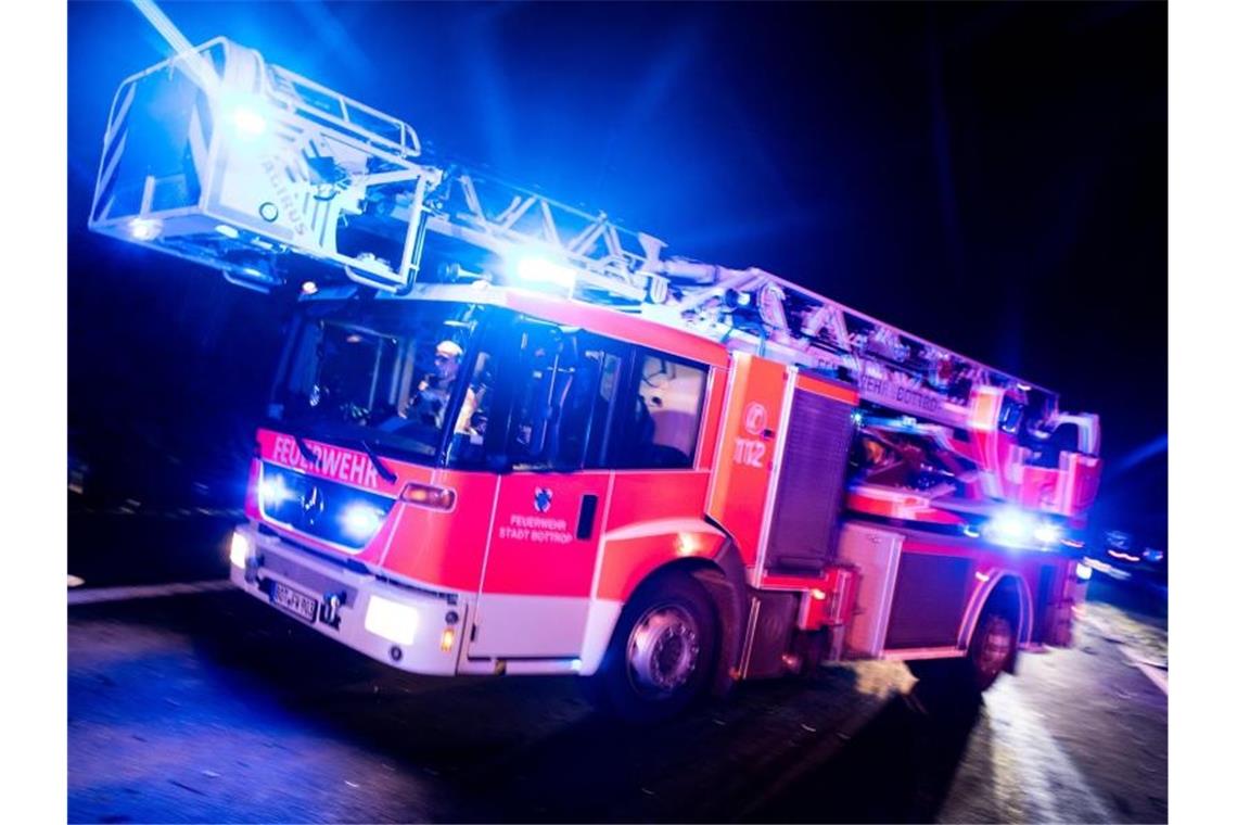 Brand in Mehrfamilienhäusern: Hunderttausende Euro Schaden Ein Drehleiterwagen der Feuerwehr fährt mit Blaulicht an einer Unfallstelle vorbei. Foto: Marcel Kusch/dpa/Illustration