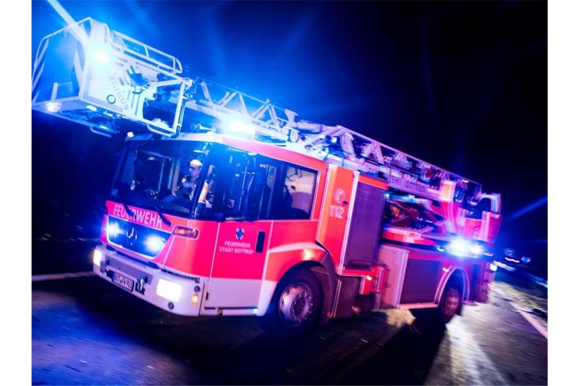 Kripo ermittelt nach zwei Bränden mit Toten in Nürtingen Ein Drehleiterwagen der Feuerwehr fährt mit Blaulicht an einer Unfallstelle vorbei. Foto: Marcel Kusch/dpa/Illustration