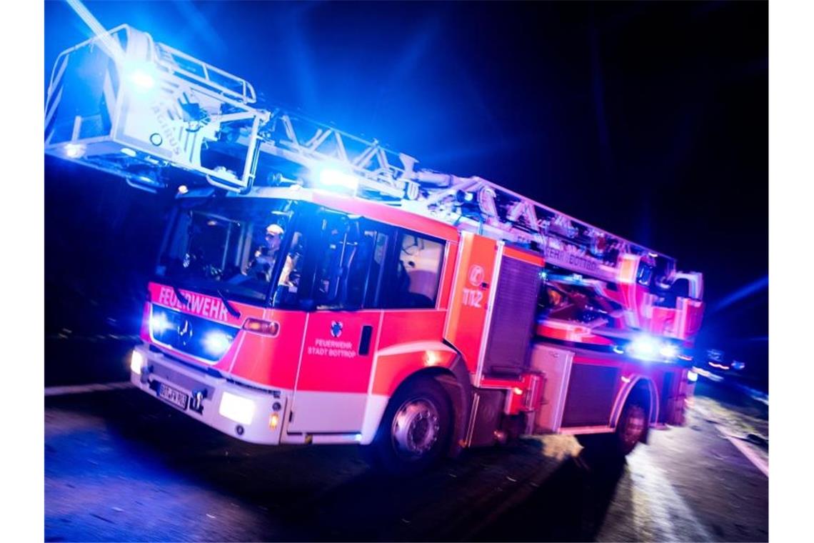 Ein Drehleiterwagen der Feuerwehr fährt mit Blaulicht an einer Unfallstelle vorbei. Foto: Marcel Kusch/dpa/Illustration