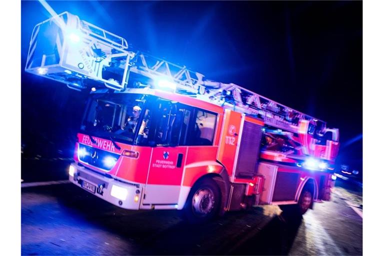 Ein Drehleiterwagen der Feuerwehr fährt mit Blaulicht an einer Unfallstelle vorbei. Foto: Marcel Kusch/dpa/Illustration