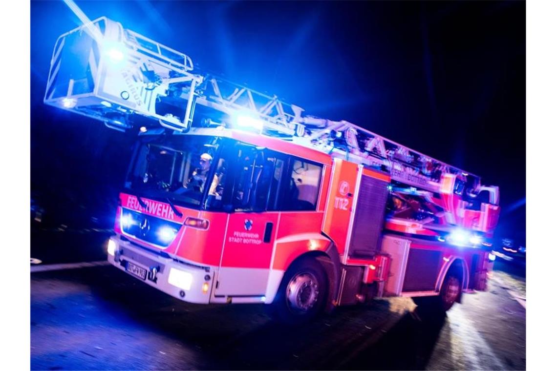 Ein Drehleiterwagen der Feuerwehr fährt mit Blaulicht an einer Unfallstelle vorbei. Foto: Marcel Kusch/dpa/Illustration