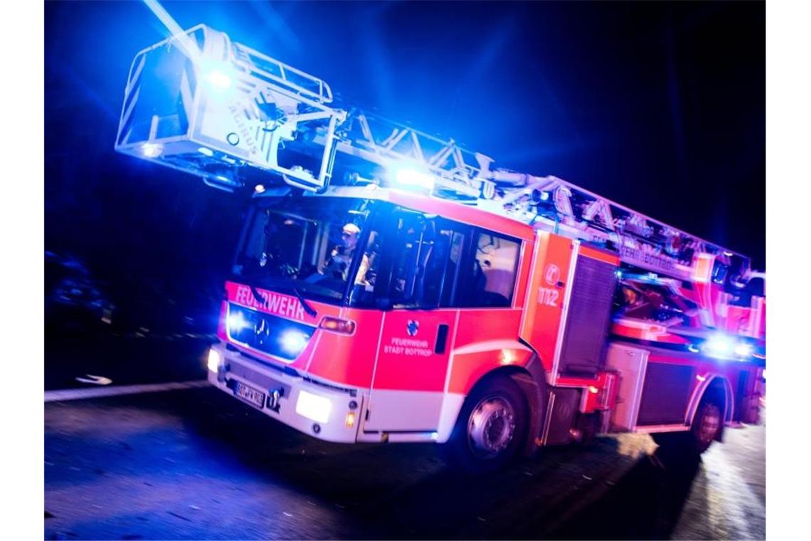 Ein Drehleiterwagen der Feuerwehr fährt mit Blaulicht an einer Unfallstelle vorbei. Foto: Marcel Kusch/dpa