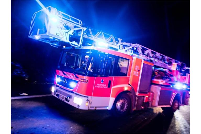 Ein Drehleiterwagen der Feuerwehr fährt mit Blaulicht an einer Unfallstelle vorbei. Foto: Marcel Kusch/dpa/Archiv