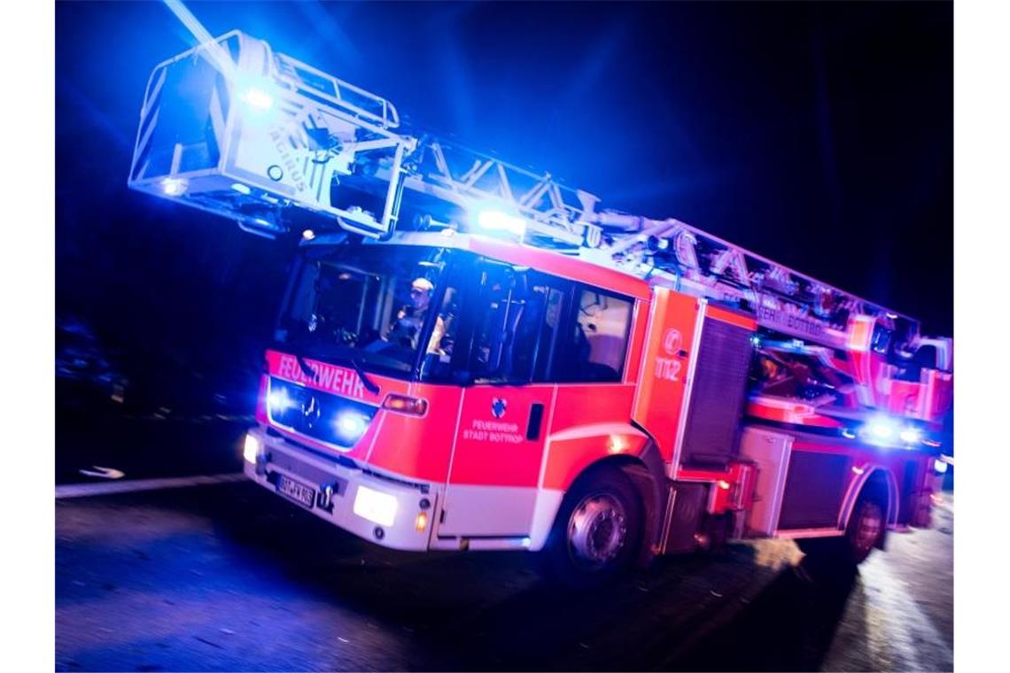 Ein Drehleiterwagen der Feuerwehr fährt mit Blaulicht an einer Unfallstelle vorbei. Foto: Marcel Kusch/dpa/Illustration