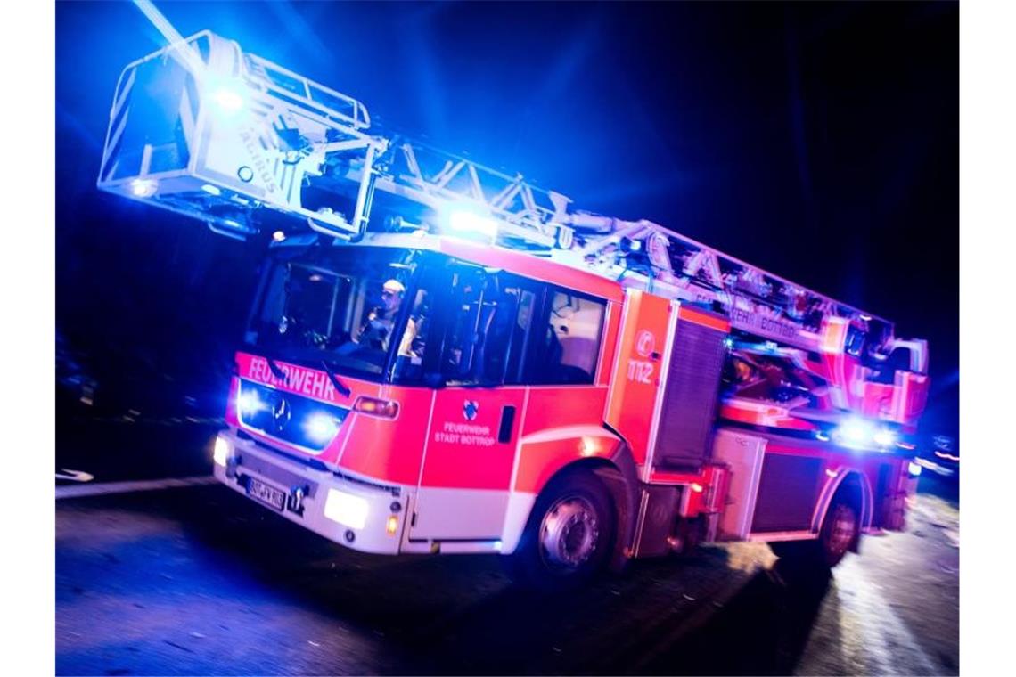 Ein Drehleiterwagen der Feuerwehr fährt mit Blaulicht an einer Unfallstelle vorbei. Foto: Marcel Kusch/dpa/Illustration