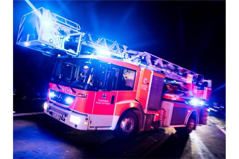Ein Drehleiterwagen der Feuerwehr fährt mit Blaulicht an einer Unfallstelle vorbei. Foto: Marcel Kusch/dpa/Illustration