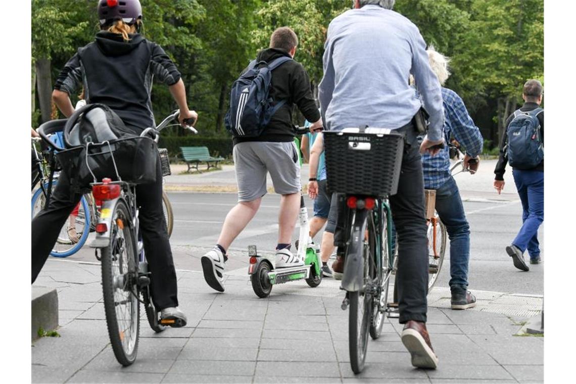 Ein E-Tretroller zwischen Fahrrädern und Autos im Straßenverkehr. Foto: Jens Kalaene