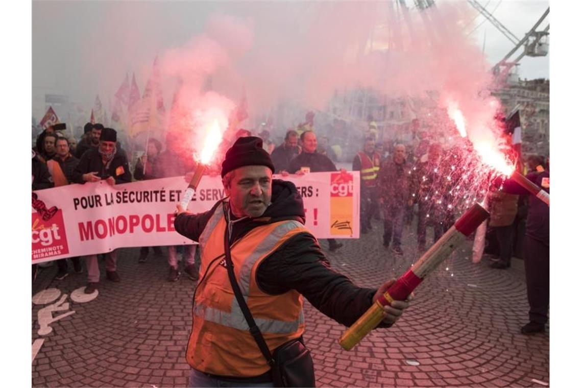 Krawalle bei Protesten gegen Rentenreform in Frankreich Ein Eisenbahner hält Fackeln während eines Streiks im Alten Hafen von Marseille. Foto: Daniel Cole/ap/dpa