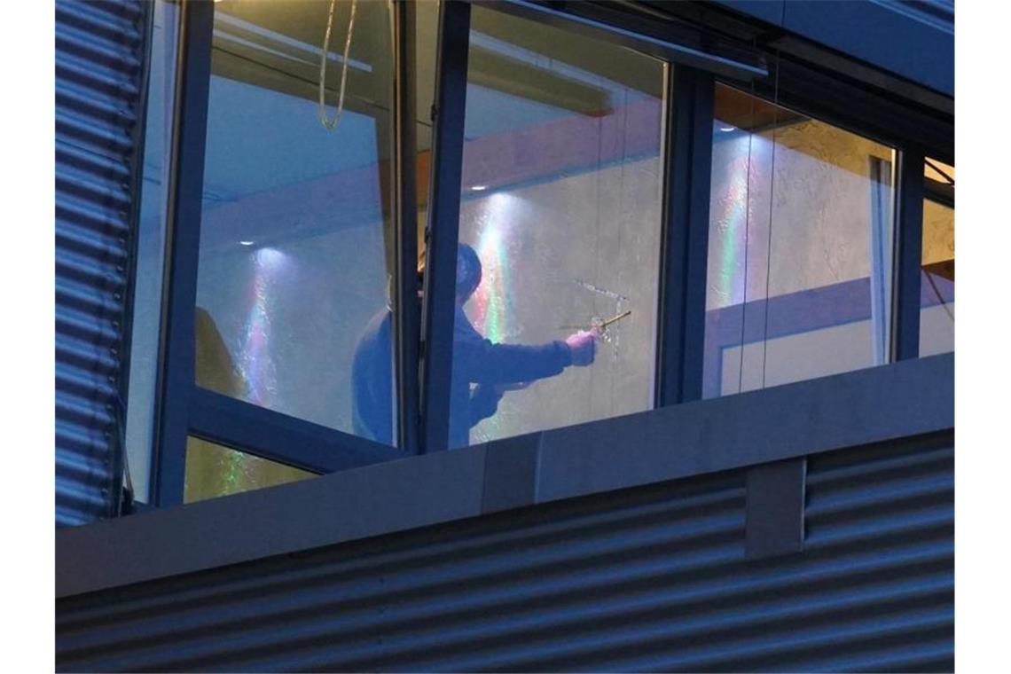 Ein Ermittler untersucht ein Einschussloch in einer Fensterscheibe. Foto: Andreas Rosar/Fotoagentur Stuttgart/dpa