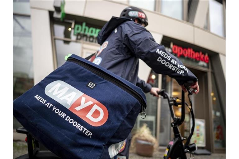 Ein Fahrer des Medikamenten-Lieferservice MAYD steht vor einer Apotheke. Per Mayd-App können Patienten rezeptfreie Medikamente bei ihrer Apotheke vor Ort bestellen. Foto: Fabian Sommer/dpa