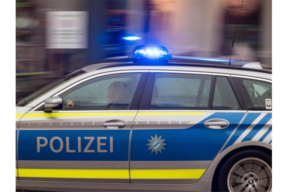 Ein Fahrzeug der bayerischen Polizei fährt mit Blaulicht durch die Innenstadt. Foto: Peter Kneffel/dpa/Symbolbild