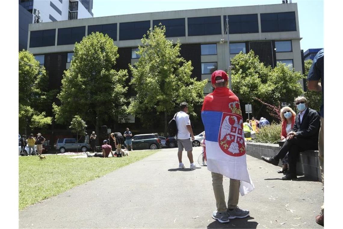 Ein Fan des serbischen Tennisspielers Novak Djokovic steht vor dem Park Hotel in Melbourne, in dem Djokovic untergebracht wird. Foto: Hamish Blair/AP/dpa