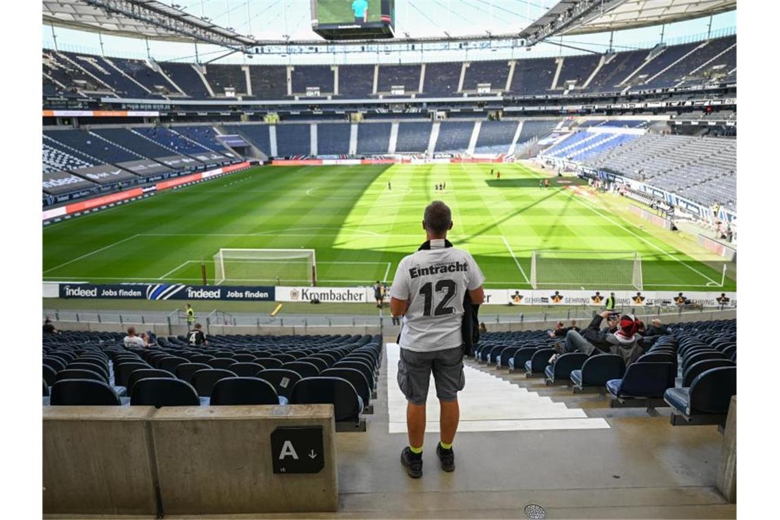 Ein Fan von Eintracht Frankfurt sucht auf der spärlich besetzten Tribüne nach seinem Sitzplatz. Foto: Arne Dedert/dpa