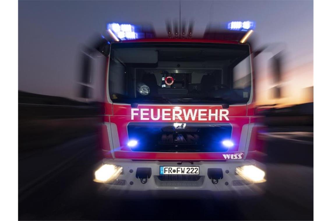 Zusammenstoß von zwei Autos: Verletzte und brennender Wagen Ein Feuerwehrfahrzeug steht mit eingeschaltetem Blaulicht auf einer Straße. Foto: Patrick Seeger/dpa/Symbolbild