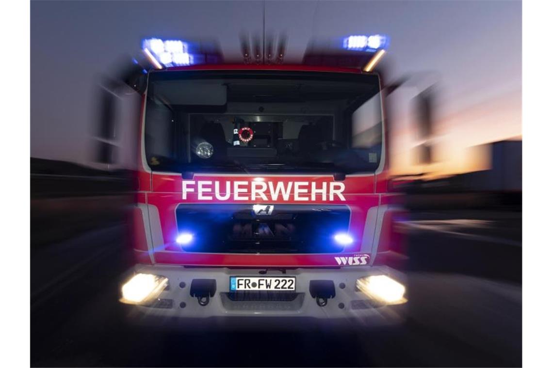 Ein Schwerverletzter bei Brand in Mehrfamilienhaus Ein Feuerwehrfahrzeug steht mit eingeschaltetem Blaulicht im Sonnenuntergang auf einer Straße. Foto: Patrick Seeger/dpa