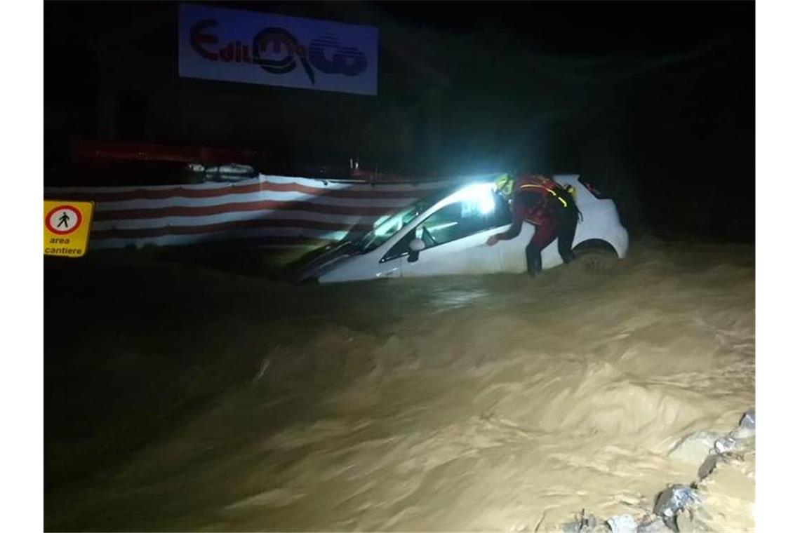 Ein Feuerwehrmann arbeitet im italienisch-französischen Alpenübergang Colle di Tenda an einem Auto, das im Eingang eines Tunnels im Hochwasser feststeckt. Foto: --/Vigili del Fuoco/dpa