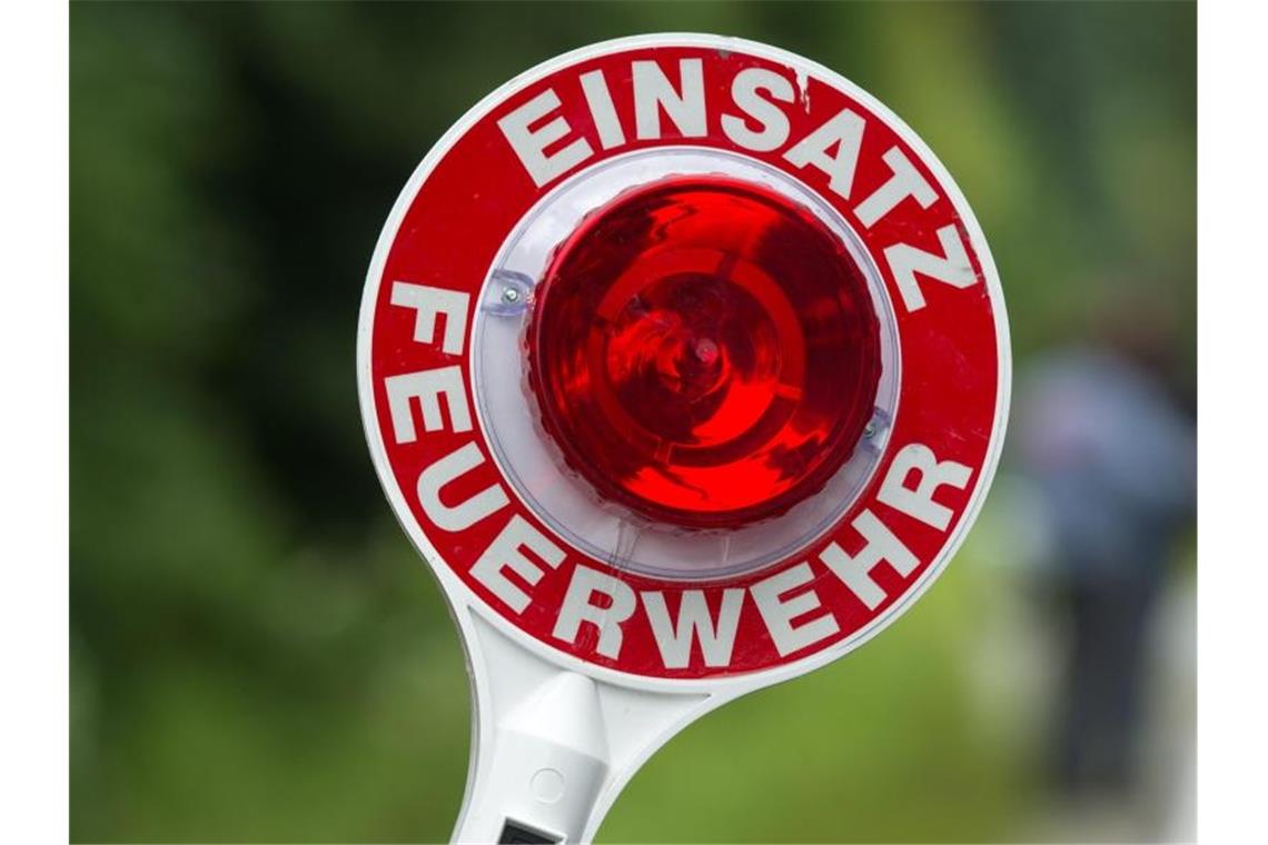 Tote Kühe bei Brand auf Bauernhof: Millionenschaden Ein Feuerwehrmann hält eine Kelle mit der Aufschrift "Einsatz Feuerwehr" in der Hand. Foto: picture alliance / dpa/Illustration