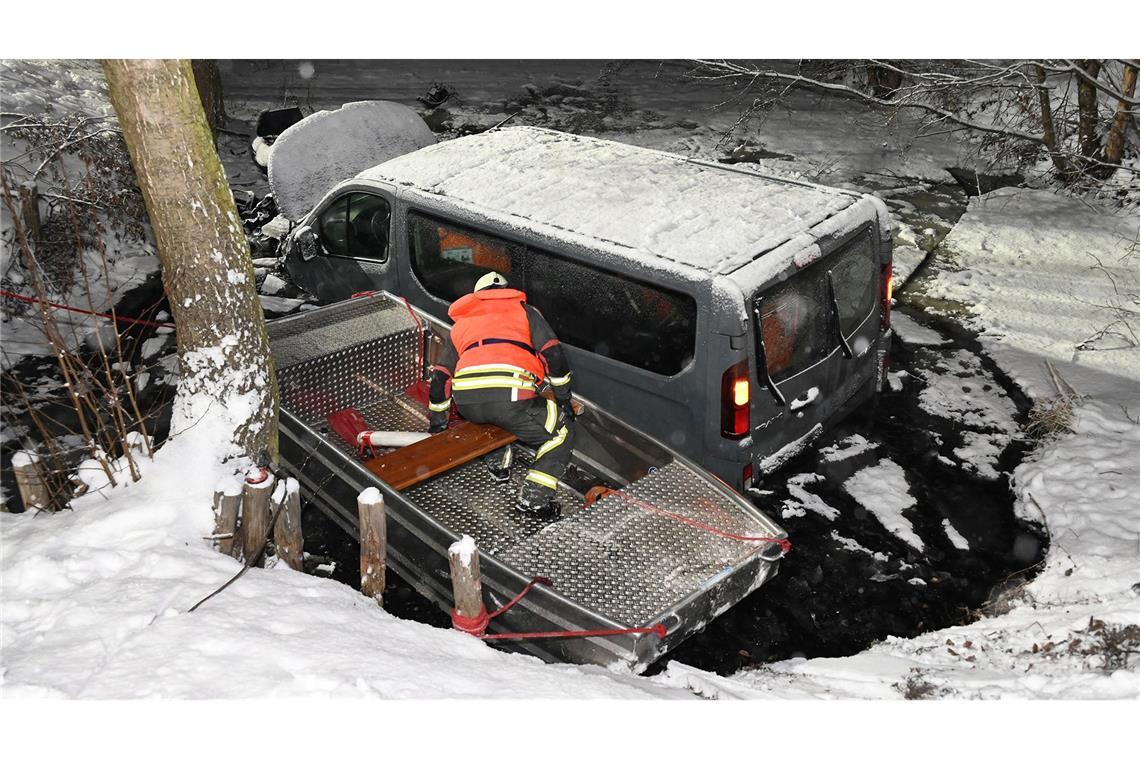 Ein Feuerwehrmann in einem Rettungsboot inspiziert einen Transporter in einem Löschteich.