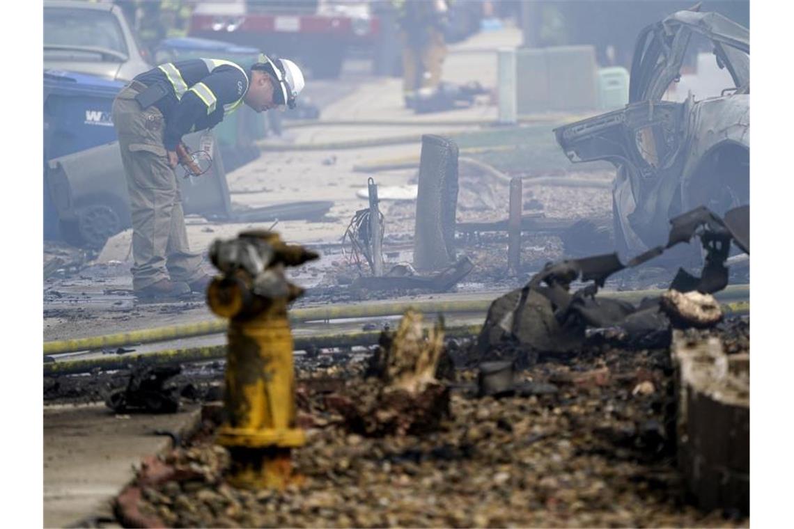 Mindestens zwei Tote nach Flugzeugabsturz auf Wohnhäuser Ein Feuerwehrmann inspiziert die Absturzstelle. Foto: Gregory Bull/AP/dpa
