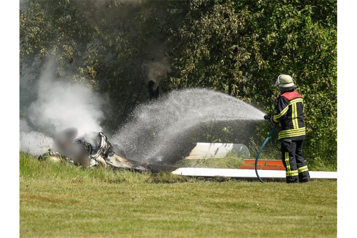 Ein Feuerwehrmann löscht an der Absturzstelle die letzten Glutreste. Foto: Hendrik Urbin/Osthessen News/dpa