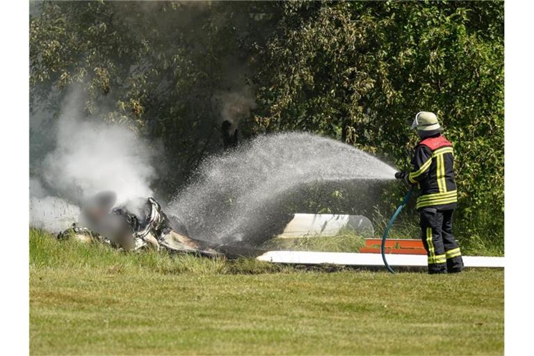 Ein Feuerwehrmann löscht an der Absturzstelle die letzten Glutreste. Foto: Hendrik Urbin/Osthessen News/dpa