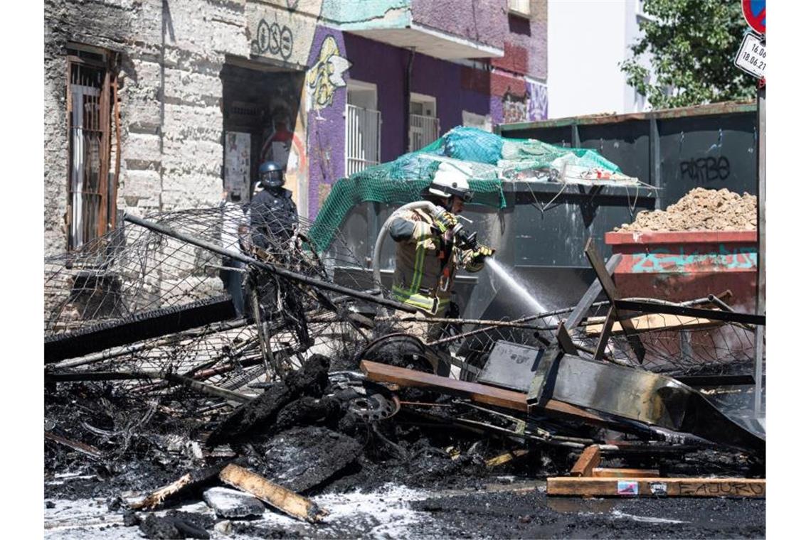 Ein Feuerwehrmann löscht eine brennende Barrikade in der Rigaer Straße in Berlin-Friedrichshain. Foto: Paul Zinken/dpa-Zentralbild/dpa