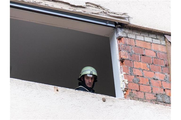 Ein Feuerwehrmann schaut nach einer Explosion aus einem beschädigten Fenster. Foto: Patrick Seeger/dpa