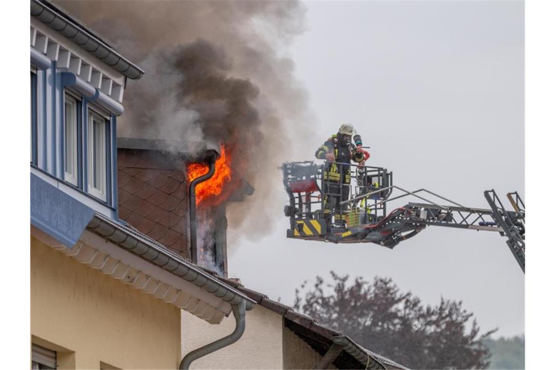 Ein Feuerwehrmann steht in einem Hebekran auf Höhe des Dachstuhlbrands. Foto: Nord-West-Media-TV/dpa