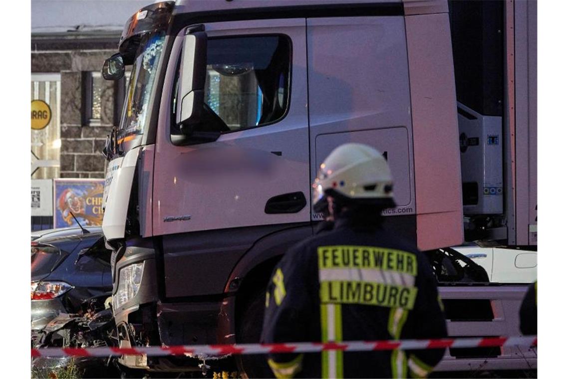 Ein Feuerwehrmann steht vor dem Lastwagen, der auf mehrere Fahrzeuge aufgefahren ist. Foto: Sascha Ditscher/dpa