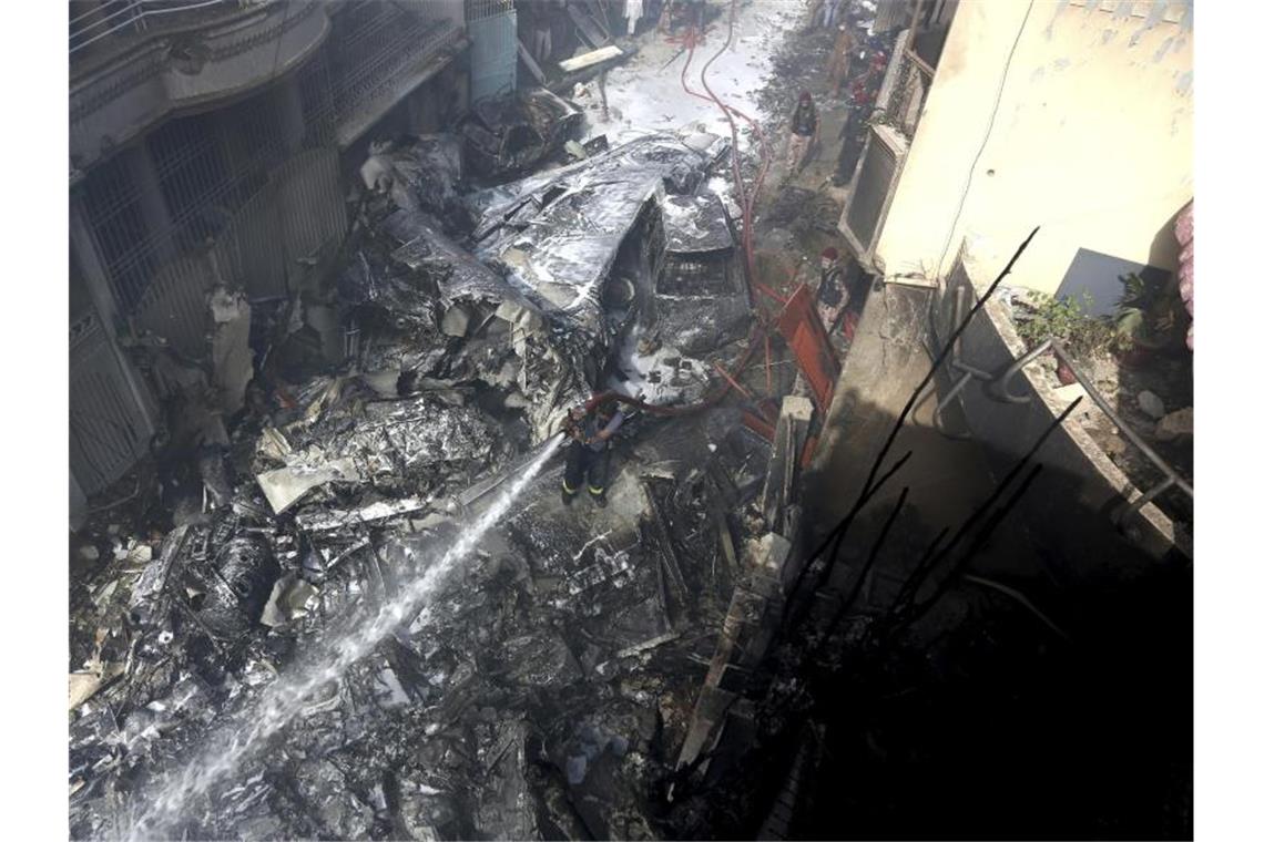 Viele Tote bei Absturz von Passagierflugzeug in Pakistan Ein Feuerwehrmann versucht, das Feuer an der Absturzstelle zu löschen. Foto: Fareed Khan/AP/dpa