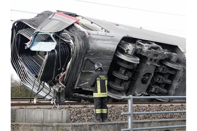 Ein Feuerwehrmann vor einem entgleisten Zugwaggon. Mehrere Waggons sollen sich überschlagen haben. Foto: Antonio Calanni/AP/dpa