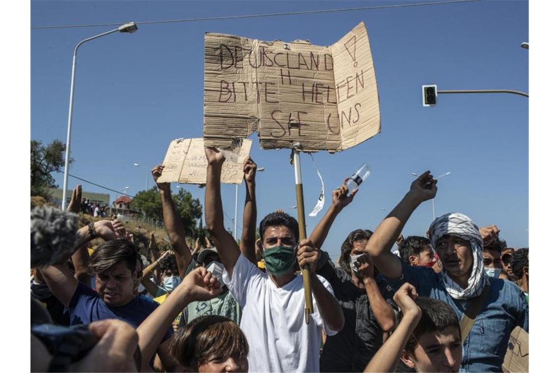 Ein Flüchtling auf Lesbos hält ein Plakat mit der Aufschrift „Deutschland, bitte helfen sie uns“. FGriechenland helfen“). Foto: Petros Giannakouris/AP/dpa