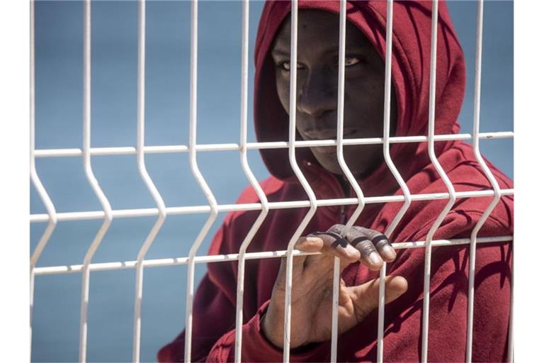 Ein Flüchtling steht an einem Zaun im Hafen von Algeciras. Die Innen- und Außenminister der EU-Staaten über eine gemeinsame Linie in den Beziehungen zu Transit- und Herkunftsstaaten von Migranten beraten. Foto: Marcos Moreno/AP/dpa