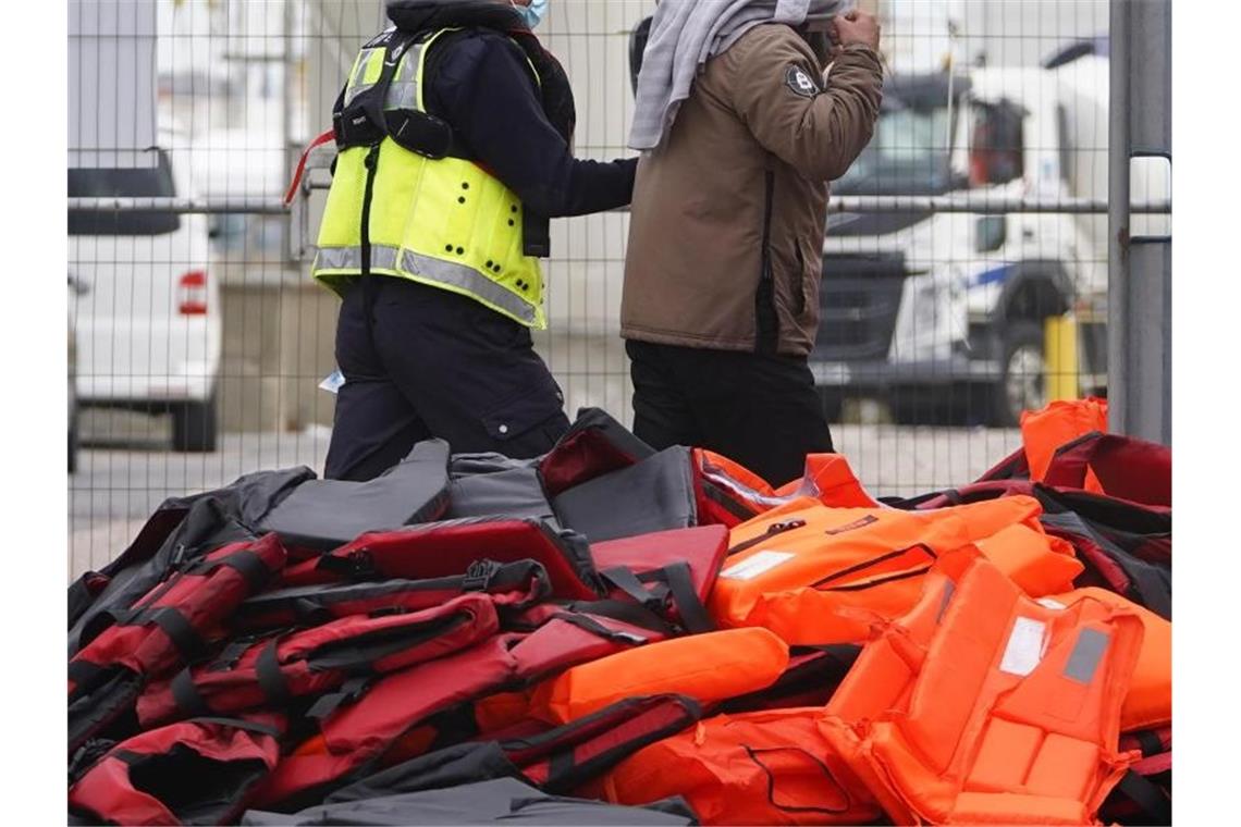 Ein Flüchtling wird von Beamten der Grenzpolizei nach Dover in Kent gebracht. Foto: Gareth Fuller/PA/dpa