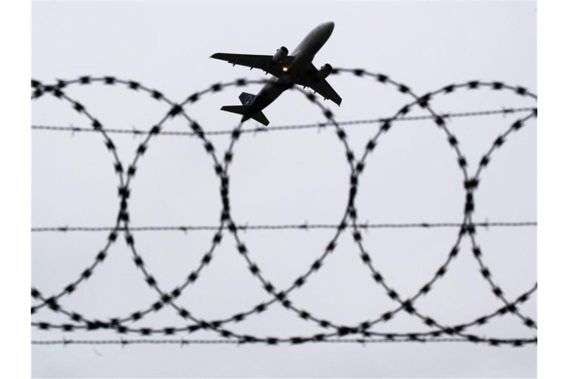 Ein Flugzeug hebt vor einem Stacheldraht in den Himmel ab. Foto: Julian Stratenschulte/dpa/Symbolbild